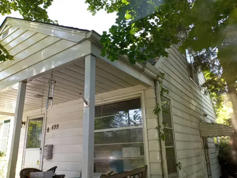 Two-storey house with green algae streaking the siding, then the same elevation cleaned