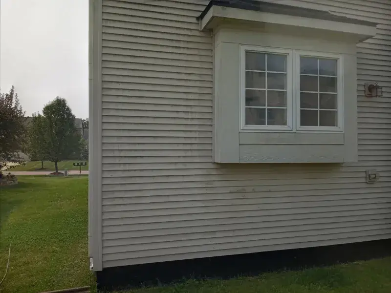 Dirty tan siding on a two-storey home, then the same siding cleaned